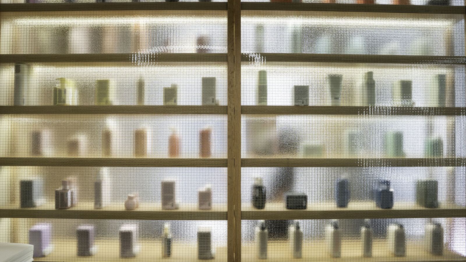 Wall of lit shelves behind wired glass, Cut & Shout